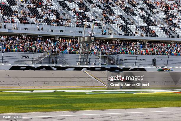Felipe Nasr driver of the Porsche Penske Motorsport Porsche 963 crosses the finish line to win the Rolex 24 at Daytona International Speedway on...