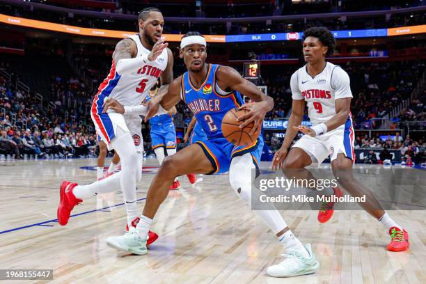 Shai Gilgeous-Alexander of the Oklahoma City Thunder is guarded by Monte Morris and Ausar Thompson of the Detroit Pistons in the first quarter of a...