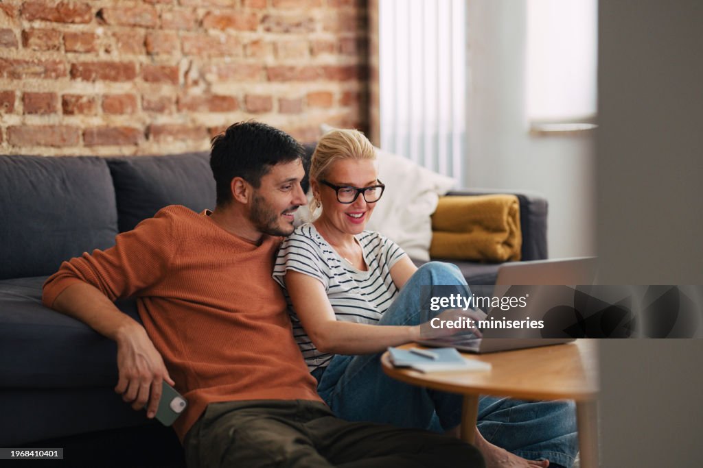 Pareja amorosa relajándose por la tarde y viendo algo en la computadora portátil