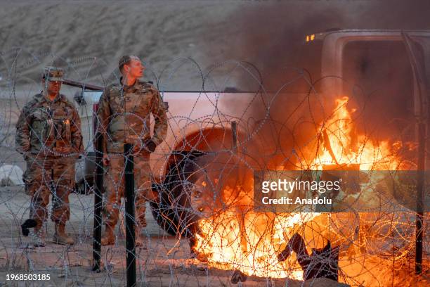Texas National Police guard burns clothes placed by migrants on barbed wire, which is used to deter irregular crossings as migrants attempt to cross...