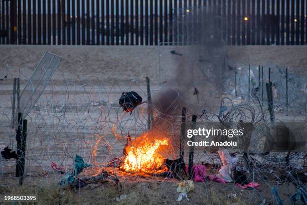 Texas National Police guard burns clothes placed by migrants on barbed wire, which is used to deter irregular crossings as migrants attempt to cross...