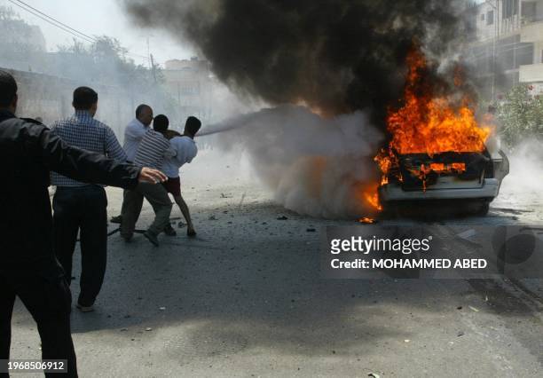 Palestinians extinguishe the car of Hamas political leader Ismail Abu Shanab after it was attacked by Israeli forces in Gaza City 21 August 2003....