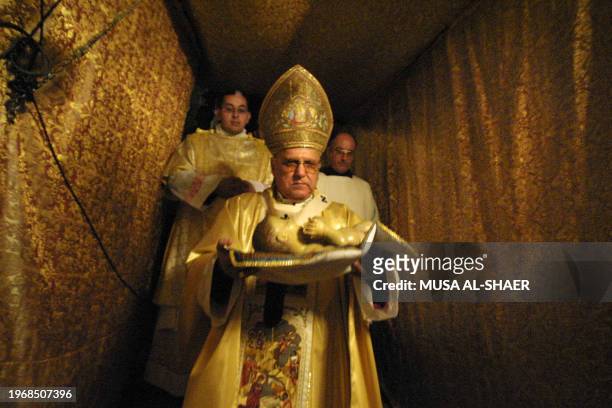 Latin Patriarch of Jerusalem Michel Sabbah carries the statue of the new born Jesus to the Holy Grotto at the end of the Christmas mass in the Holy...