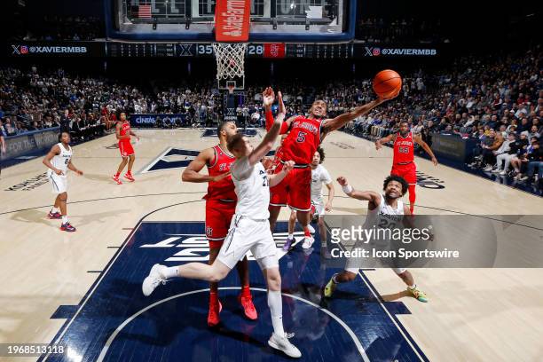 St. John's Red Storm guard Daniss Jenkins rebounds between Xavier Musketeers forward Sasa Ciani and guard Dayvion McKnight during a college...