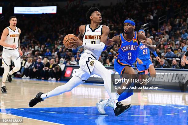 Peyton Watson of the Denver Nuggets drives the lane against Shai Gilgeous-Alexander of the Oklahoma City Thunder during the second half at Paycom...