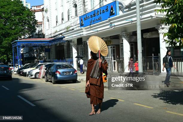 Buddhist monk covers his face from the sun as he crosses a street in Yangon on February 1 before a "silent strike" was due to start at 10am. Myanmar...