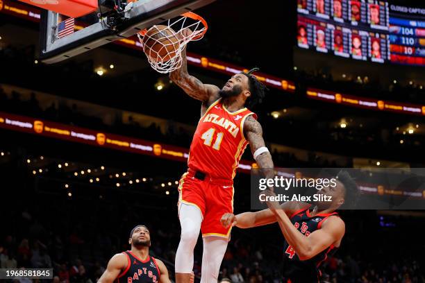 Saddiq Bey of the Atlanta Hawks dunks over Scottie Barnes of the Toronto Raptors during the first half at State Farm Arena on January 28, 2024 in...
