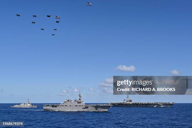 Formation of aircraft from the USS Carl Vinson aircraft carrier conducts a flyover past a flotilla, including the USS Theodore Roosevelt aircraft...