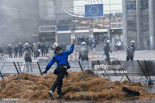 Demonstrator throws an egg towards Belgian police officers near the entrance of the European Parliament building during the farmer protest action in...