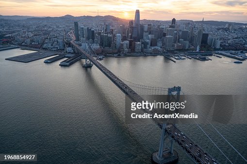 Aerial view of city skyline, calm bay and bridge at sunset