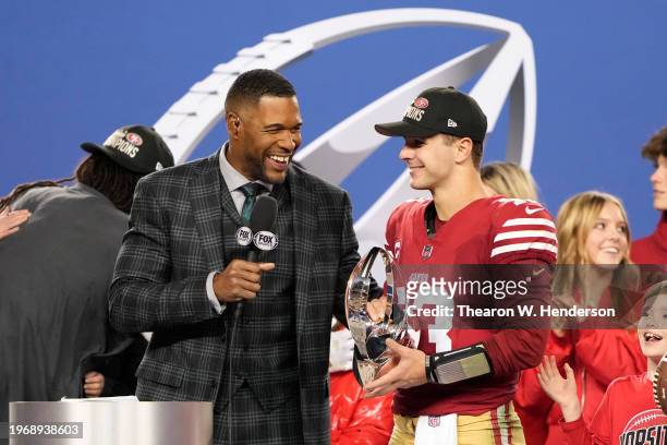 Brock Purdy of the San Francisco 49ers is interviewed by Michael Strahan while holding the George Halas Trophy after defeating the Detroit Lions...