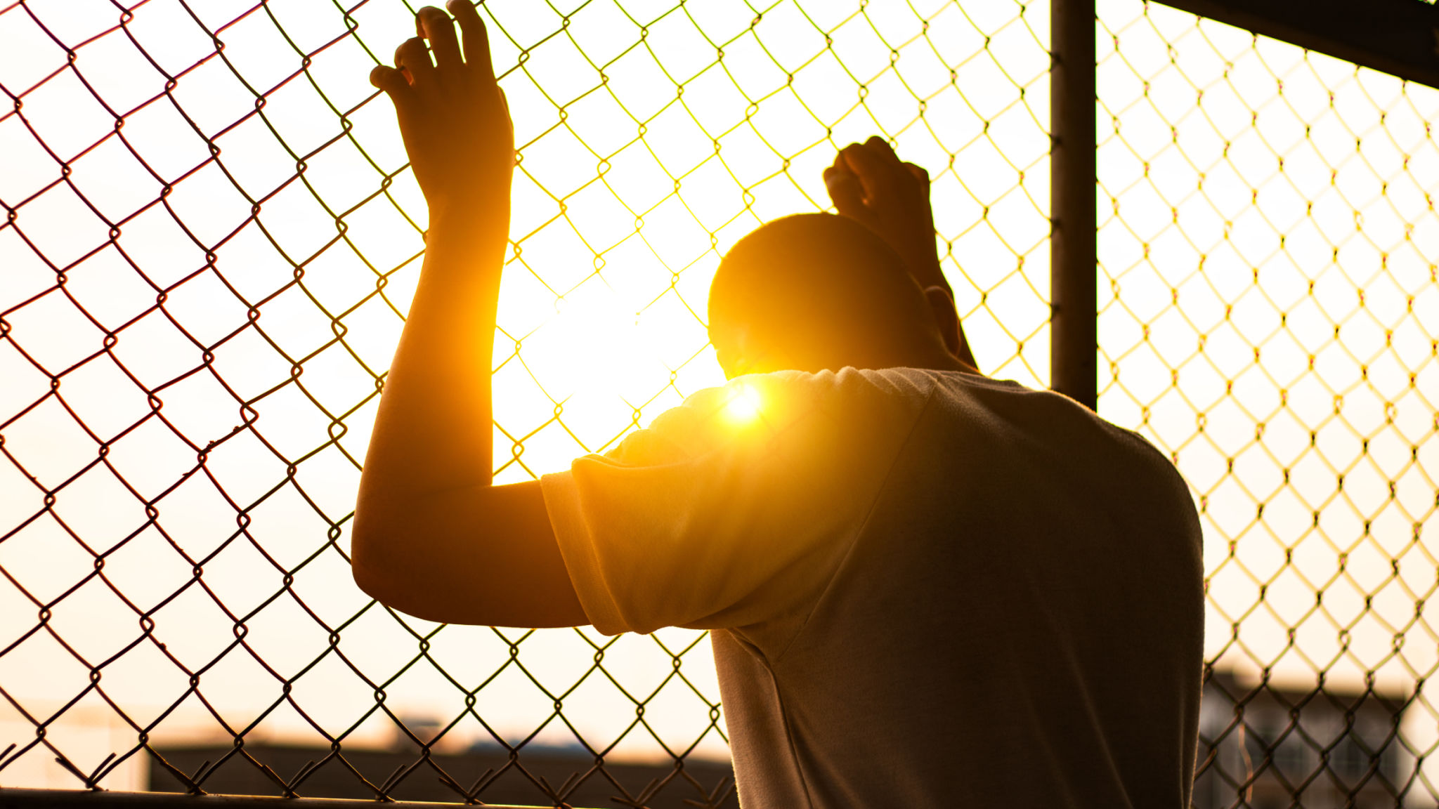 Silhouette of a man behind the fence, Silhouette photo of feeling upset, sad, unhappy or disappoint crying. Young people mental health care problem lifestyle concept, frustrated standing hopelessly Silhouette of a man behind the fence, Silhouette photo of feeling upset, sad, unhappy or disappoint crying. Young people mental health care problem lifestyle concept, frustrated standing hopelessly