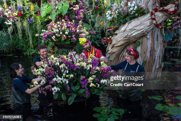 Staff members pose for the media as they pretend to tend to flowers during a staged photocall to launch the 'Kew Orchid Festival: Madagascar' display...