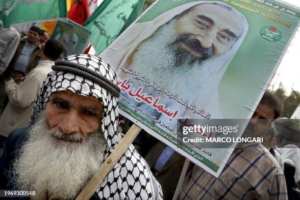 An elderly Palestinian man carries a poster showing late spiritual leader Sheikh Ahmed Yassin 30 March 2004 in Khan Yunes in the southern Gaza Strip...