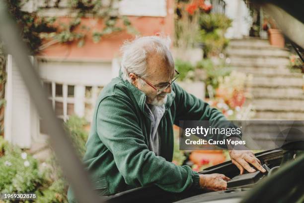 senior man using jumper cables to start a car battery - starthilfe stock-fotos und bilder