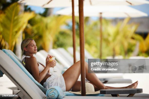 young woman drinking juice on deck chair at the beach. - meeru island stockfoto's en -beelden