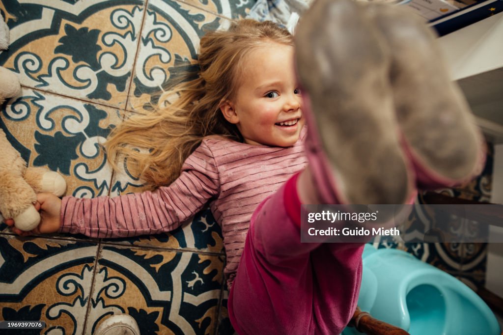 Happy cute girl lying on the ground in bathroom at home.
