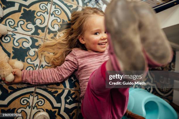 happy cute girl lying on the ground in bathroom at home. - childrens closet stockfoto's en -beelden