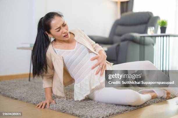 asian pregnant woman facing an unfortunate slip and falling down in living room  accident at home. - petticoat stock pictures, royalty-free photos & images