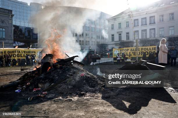 Statue lies by a fire after being pulled down by demonstrators at the Place de Luxembourg near the European Parliament building in Brussels on...