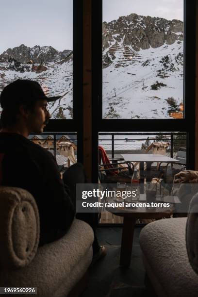 adult man sitting inside a cafe with views of the snowy mountains - nevada winter stock pictures, royalty-free photos & images