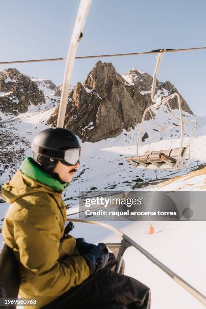 adult man sitting on a chairlift at a ski resort in winter - torres stock pictures, royalty-free photos & images
