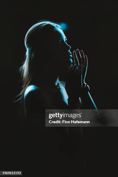 beautiful woman bathed in blue light posing dreamily with her arms on her face. magical cinematic portrait. - rim light portrait stock pictures, royalty-free photos & images
