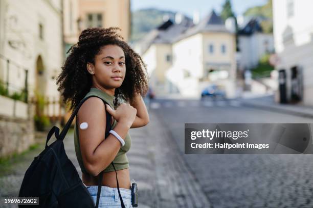 teenage diabetic student in the city going to school. teenage girl wearing insulin pump and continuous glucose monitor sensor on her arm to monitor her blood sugar level in real time, deliver dose of insulin. - fühler stock-fotos und bilder