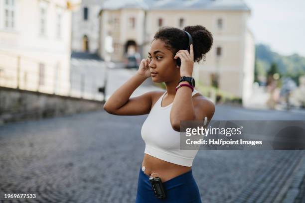 beautiful diabetic girl in activewear working out in the city. diabetic teenage girl with continuous glucose monitor and insulin pump exercising. - city sensors stock pictures, royalty-free photos & images