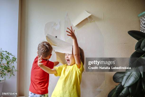 shared family project: sibling teamwork in stripping wallpaper for room transformation. - menschliche erzeugnisse stock-fotos und bilder