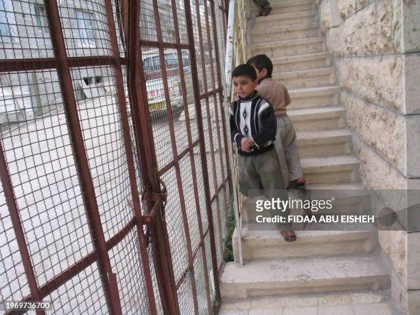 Sharif et Walid Abu Eisheh se tiennent dans l'escalier de leur maison en face de la colonie de Tel Romeida, le 14 décembre 2003. La famille Abu...