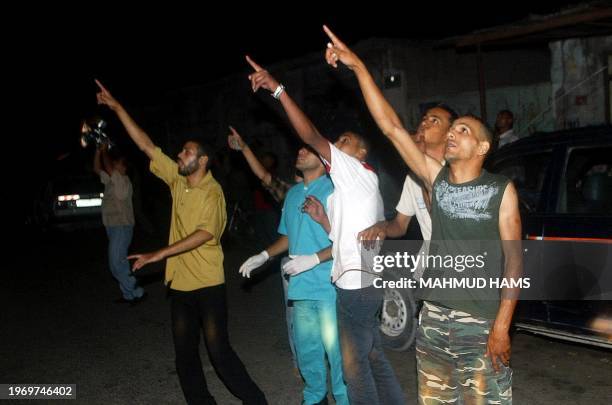 Palestinians point to an Israeli helicopter gunship which carried out two air raids on Gaza City's Zeitoun neighborhood late Friday 18 June 2004,...