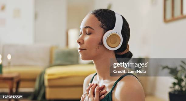 woman, meditation and yoga in headphones listening to calm music, holistic exercise and peace in living room. young person with audio podcast, dream of health and relax in spiritual wellness at home - music room stockfoto's en -beelden