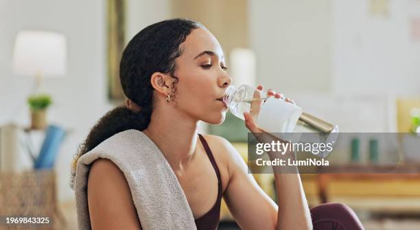 woman, exercise and drinking water on floor in home with diet, hydration or liquid for health detox. girl, person and bottle for workout, nutrition and wellness with training for fitness in house - eletrólito imagens e fotografias de stock