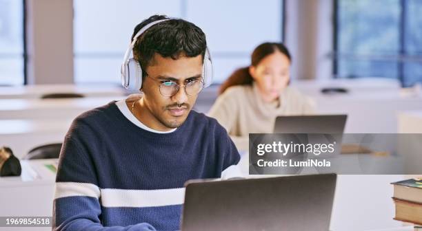 mann, student in kopfhörern und laptop für den unterricht im klassenzimmer, e-learning und studium oder forschung an der hochschule. menschen, die auf dem computer für universitätsinformationen oder stipendienaufsätze lesen und zuhören - schulische prüfung stock-fotos und bilder