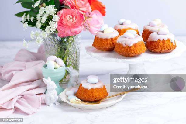 homemade delicious mini lemon bundt cakes and chocolate eggs on a easter table with fresh spring flowers. - bundt cake stock pictures, royalty-free photos & images