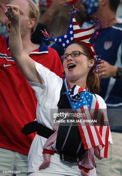 Woman holding her baby cheers for the USA ahead of the Poland-USA Group D match at the 2002 FIFA World Cup Korea/Japan in Daejeon, 14 June 2002. It...