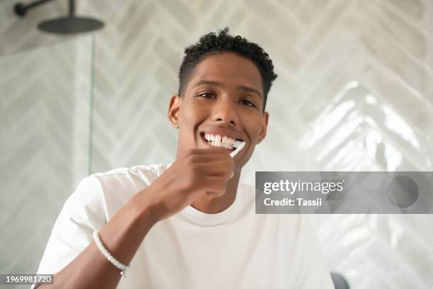 portrait, bathroom or man brushing teeth with dental toothpaste for healthy oral hygiene grooming. shower, morning or face of male person cleaning mouth with toothbrush for health or wellness in home - fresh breath stockfoto's en -beelden