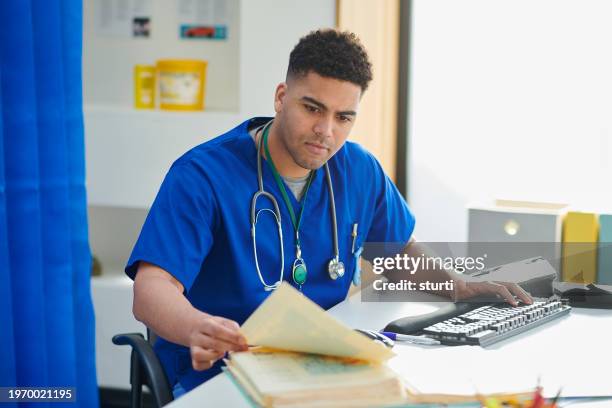 junior doctor catching up on paperwork - medisch document stockfoto's en -beelden
