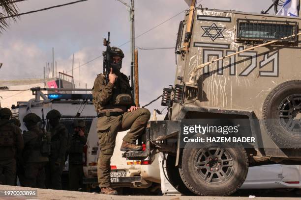 Member of the Israeli security forces stands guard as others check a car that was reportedly used by a Palestinian to carry out a thwarted ramming...