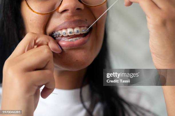 braces, floss and closeup of woman with dental health, wellness or hygiene morning routine. smile, dentistry and zoom of young female person cleaning teeth for fresh oral mouth treatment at home. - dental braces stock pictures, royalty-free photos & images