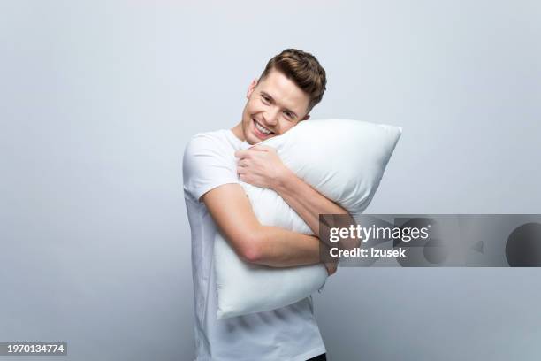 portrait of young man hugging pillow - object-on-pillow stock pictures, royalty-free photos & images