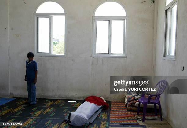 Palestinian boy looks at the body of 21-year-old Mohammad Salman Abu Hashish, draped in a national flag, before his funeral at a mosque in Beit Lahia...