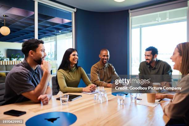 smiling group of diverse businesspeople having a board room meeting - multi ethnic business people having discussion at table in board room stockfoto's en -beelden