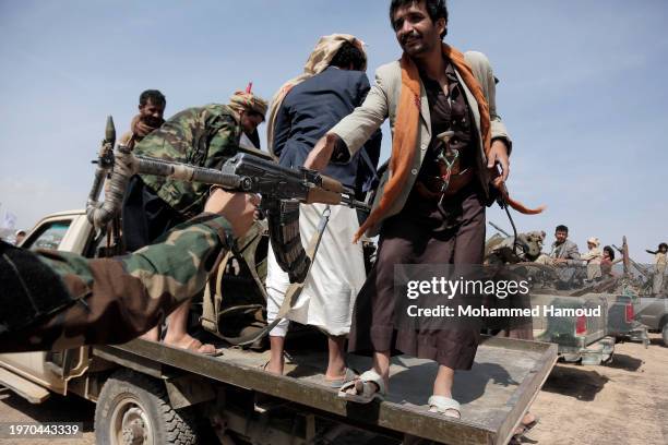 Yemen's Houthi fighter hands another a gun while participating in a weaponized rally and parade against the America-Britain airstrikes and in...