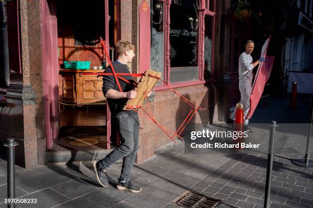 Staff bring out street tables and fittings belonging to their retail business in Chinatown, on 1st February 2024, in London, England.