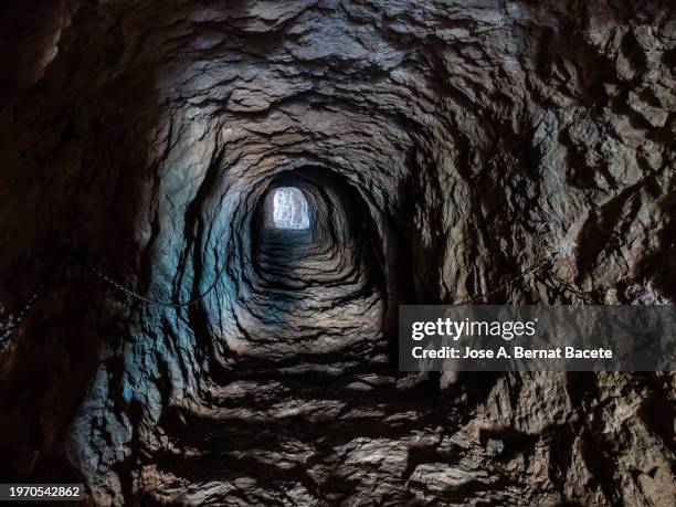 pedestrian tunnel between rocks that crosses a mountain to access the top of the peñon de ifach - grotte stock-fotos und bilder