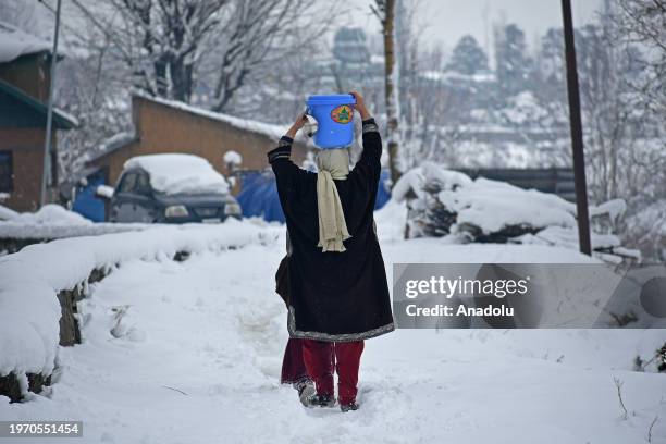 Woman carries a water bucket as she makes her way through the snow covered road in north Kashmir's Tangmarg in Baramulla district on February 01,...