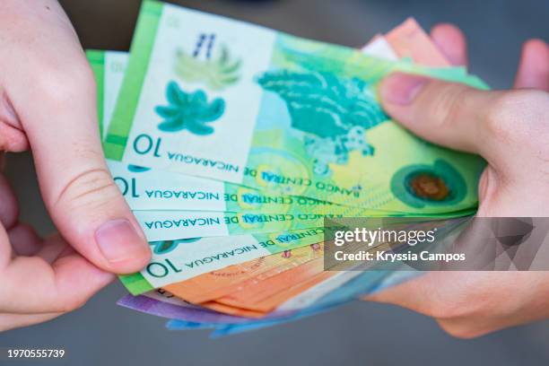 man's hands holding nicaraguan córdoba bills - san juan del sur stock pictures, royalty-free photos & images