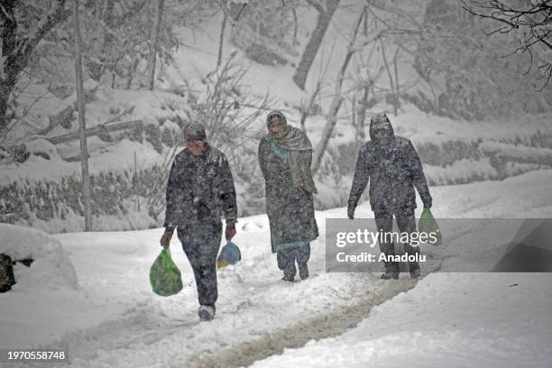 People walk as it snows in north Kashmir's Tangmarg in Baramulla district on February 01, 2024.The prolonged dry weather ends as Kashmir valley...